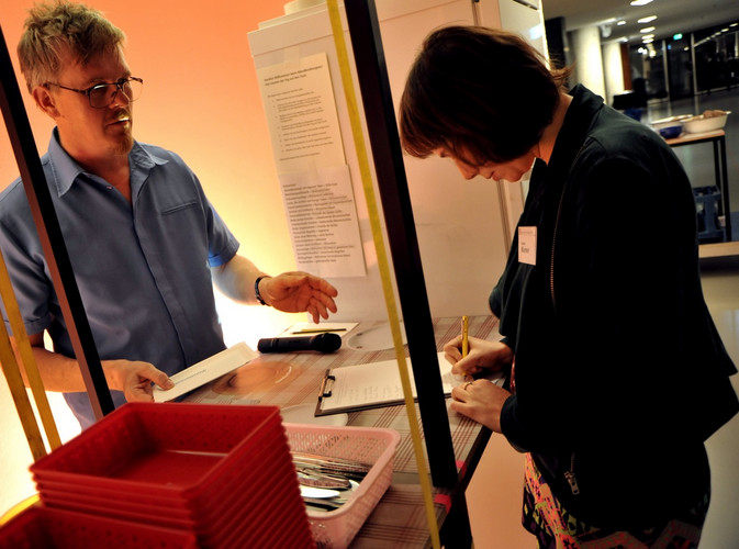 Two people interacting with the Installation "Abendbrot-Kongress": one of them signing a form.