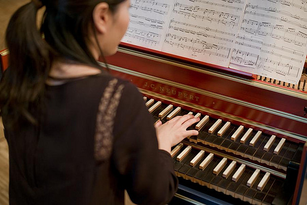 Eine junge Frau spielt auf einem Cembalo.