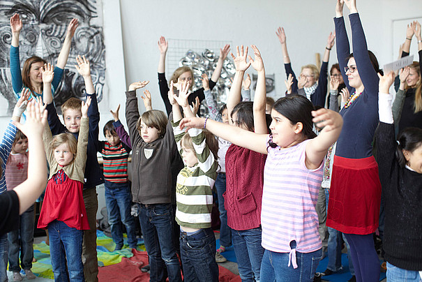 Eine Gruppe kleine Kinder heben ihre Hände aus Freude in die Luft.