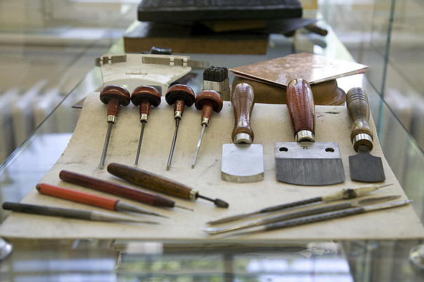 Verschiedene Werkzeuge aus der Druckwerkstatt der Faklutät Bildende Kunst liegen auf einem Tisch.