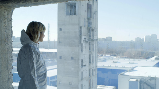 Filmstill Person im Schutzanzug Blick über die Stadt