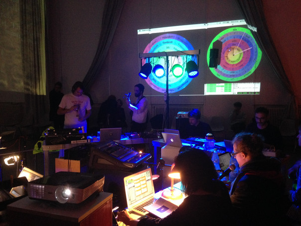Roundtable with students in front of their laptops. Headlights and colourful projections on the wall.