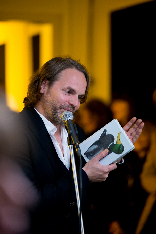 Portrait of Jan Verwoert who holds the publication &quot;No New Kind of Duck&quot; in his hand; the cover features a surreal duck.