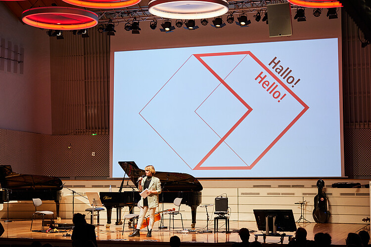 Emily Thomey (cultural journalist) welcomes the new students as moderator in the Concert Hall of the UdK Berlin.