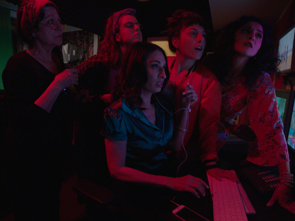 Foto: Nino Klingler, Zeynep Tuna Video still featuring some people watching something unknown on a light reflecting screen.