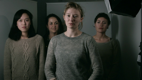 Four women in grey clothes facing the camera.