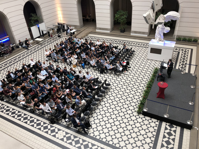 Auf Stühlen sitzende Teilnehmende im Lichthof der Technischen Universität Berlin