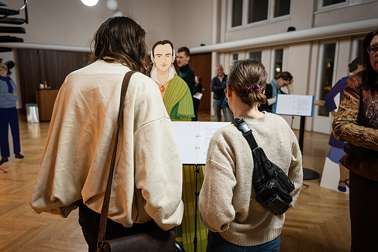Zwei Personen betrachten die Ausstellen "Standing Ovation" im Vorraum des Konzertsaals.