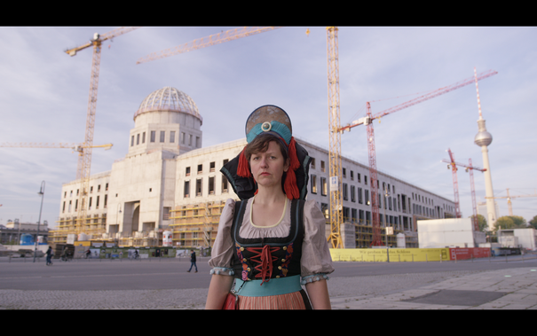 A woman in traditional costume in front of the Humboldtforum in Berlin.