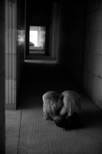 The two performers naked and huddled in an empty building.