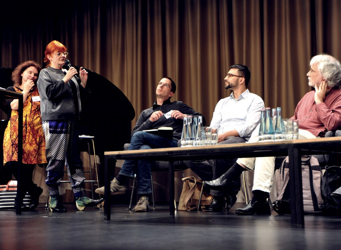 Discussion between five People behind table of stage