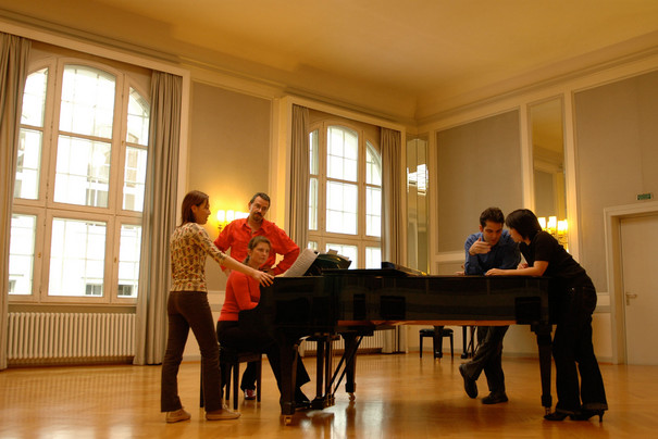 Eine Gruppe von Studierenden zusammen mit Prof. Bauni beim Einüben von Gesangsliteratur