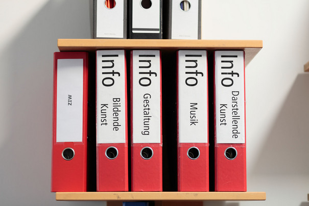 Fünf rote Aktenordner mit den Beschriftungen &quot;Darstellende Kunst&quot;, &quot;Musik&quot;, &quot;Gestaltung&quot;, &quot;Bildende Kunst&quot; und &quot;ZIW&quot;.