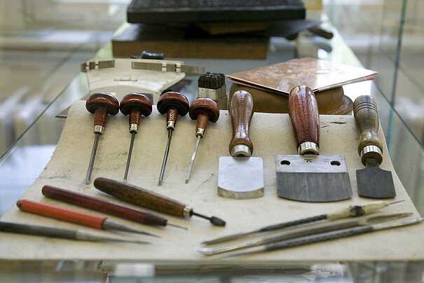 Verschiedene Werkzeuge aus der Druckwerkstatt der Faklutät Bildende Kunst liegen auf einem Tisch.