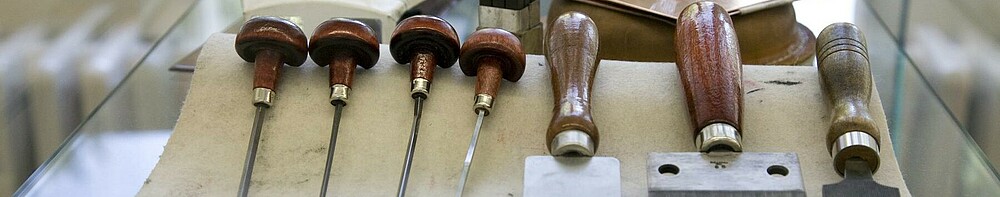Verschiedene Werkzeuge aus der Druckwerkstatt der Faklutät Bildende Kunst liegen auf einem Tisch.