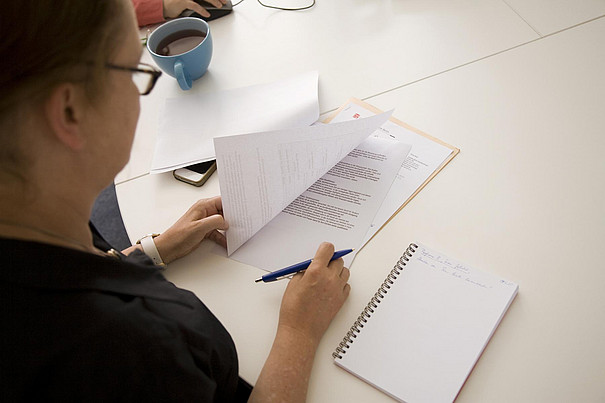 Foto: Jo Neander Eine Mitarbeiterin macht sich Notizen zu einem ausgedruckten Papier.