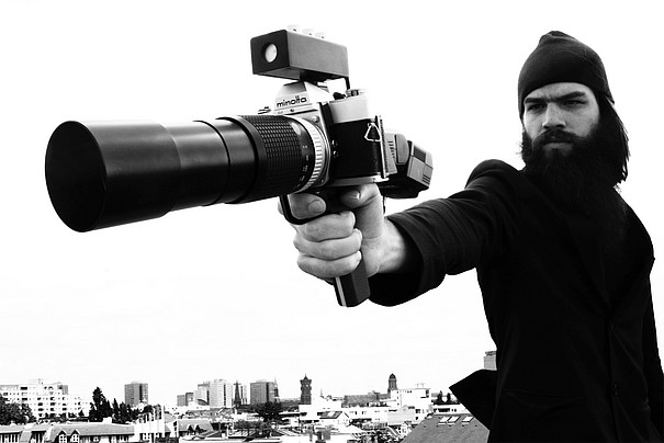Eine Person, die eine Kamera mit einem Riesenobjektiv wie eine Schusswaffe hält.